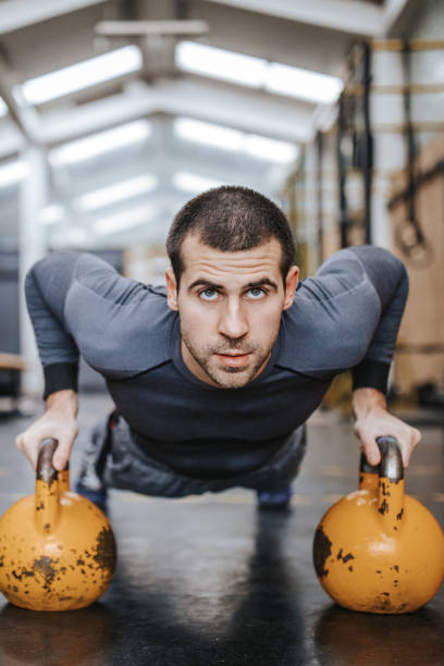 istock Athlete doing push-ups on kettle bells in gym 1127720996