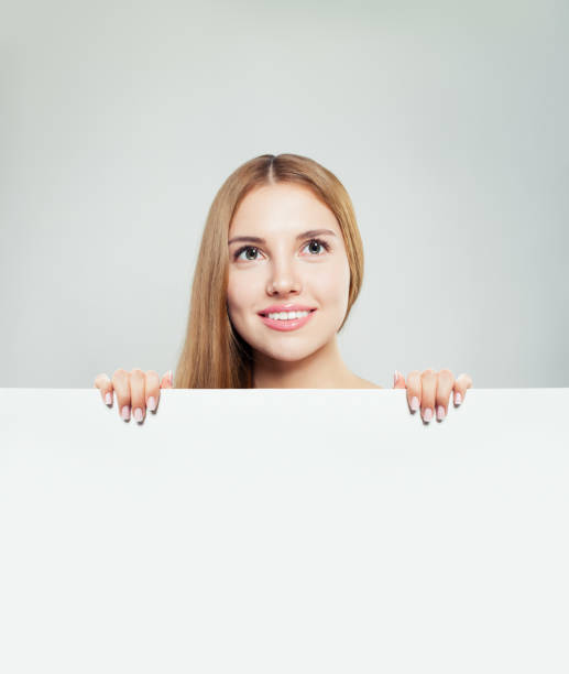 istock Happy woman looking up and holding white empty paper board background with copy space 1127723989