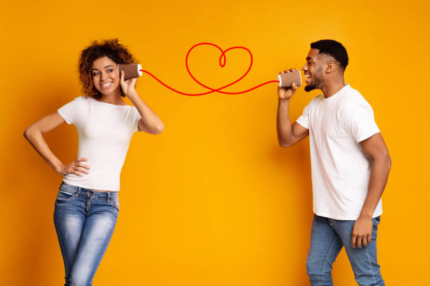 istock Young black couple with can phone on orange background 1127724365