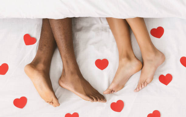毛布の下のベッドに横になっているカップルの足を愛する - bed couple human foot heterosexual couple ストックフォトと画像