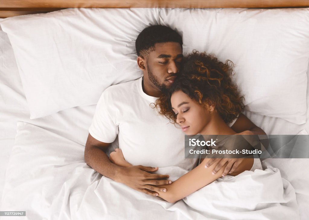 Young black couple sleeping together in bed Lovely black couple lying in white bed, sleeping together, top view Couple - Relationship Stock Photo