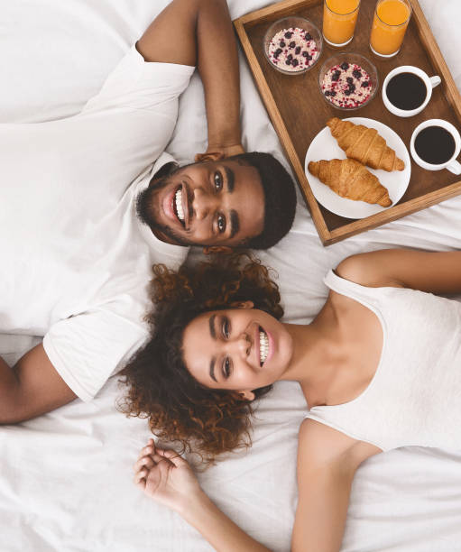 heureux jeune couple manger matin petit déjeuner au lit - valentines day romance boyfriend vertical photos et images de collection