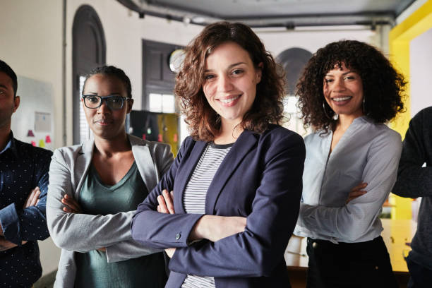 istock Confident young woman with her team at office 1127726441