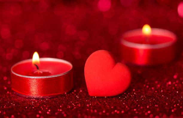 istock Romantic Valentine's Day. Lit scented candles and red heart on bright sparkling background with bokeh effect 1127728311