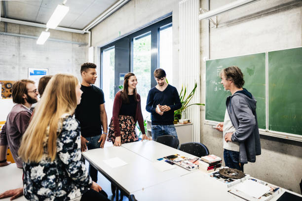 University Tutor Talking With Students In Front Of Blackbaord