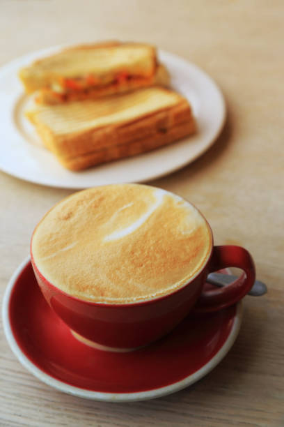 istock Breakfast set with latte coffee in red cup and sandwich on rustic wooden table. 1127729180