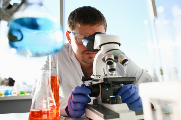 portrait d’un jeune chimiste dans jumelles - microscope medical exam healthcare and medicine science photos et images de collection