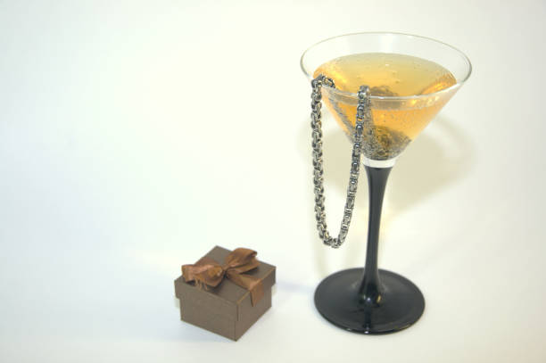 istock A glass of champagne with a chain inside and a small gift box. 1127731017