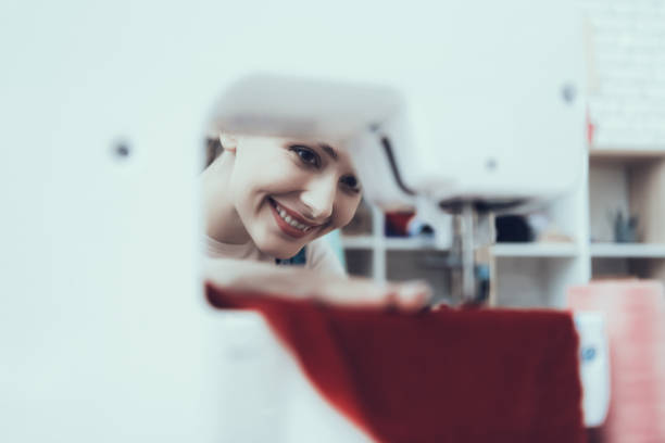 Young Dressmaker Woman. Sews clothes on Sewing Machine. help of assistants. Best Job. Professional Work. Seamstress Workplace. smiling Woman. close up. job sewing machine. woman at work