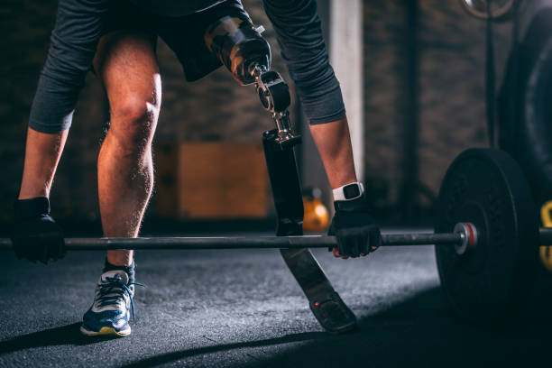 istock Disabled young athlete with a prosthetic doing a dead-lifting a barbell in a gym gym 1127734675