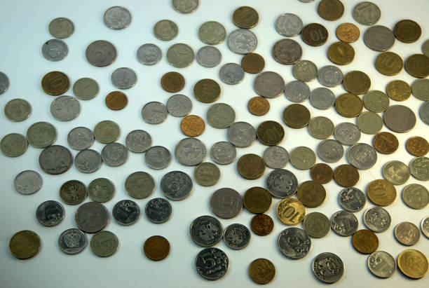 Coins laid out in a chaotic manner on a white background. Close up.