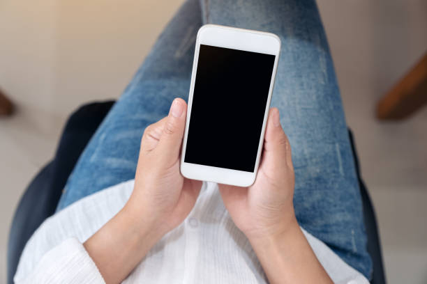 istock Top view mockup image of hands holding and using a white mobile phone with blank screen while sitting 1127736588