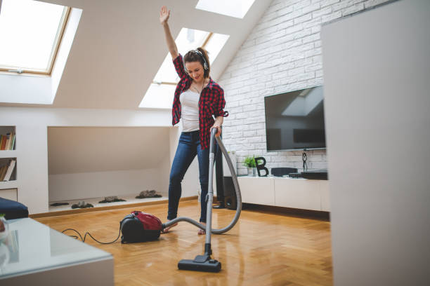 istock Young woman using vacuum cleaner to clean house 1127738395