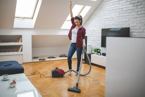 istock Young woman using vacuum cleaner to clean house 1127738614