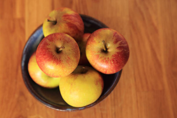 istock Composition with Yellow Red Apples in ceramic bowl top view on wooden background. 1127739773
