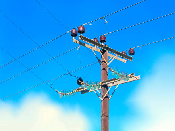 Wooden pole of power line, porcelain and glass insulators Wooden pole of power line with electrical insulators of porcelain and glass. It isolated on blue sky. Close-up. utility pole with power lines close up stock pictures, royalty-free photos & images
