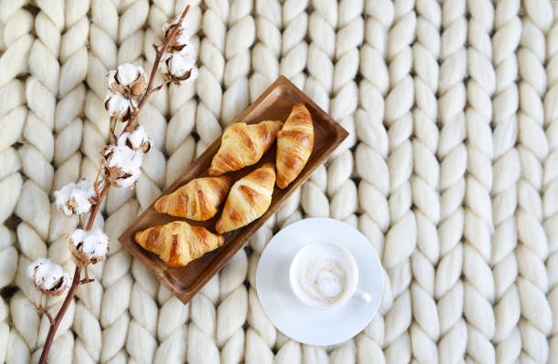 istock Cup with cappuccino and croissants. white merino woolen blanket 1127744450