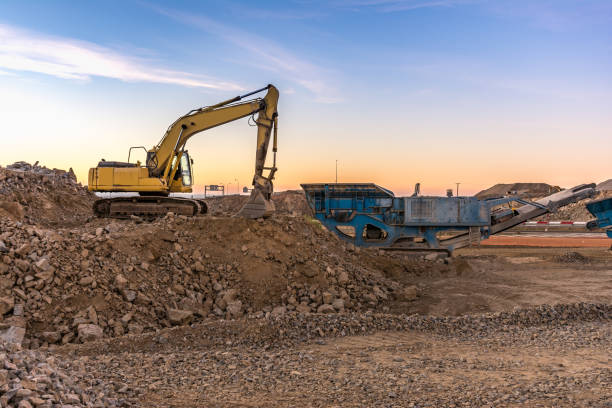 istock Machinery in a quarry: excavator and stone pulverizing machine 1127746830