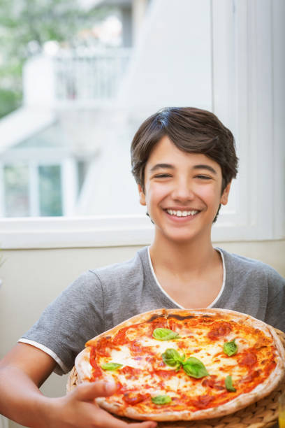 istock Happy teen boy eating pizza 1127748736