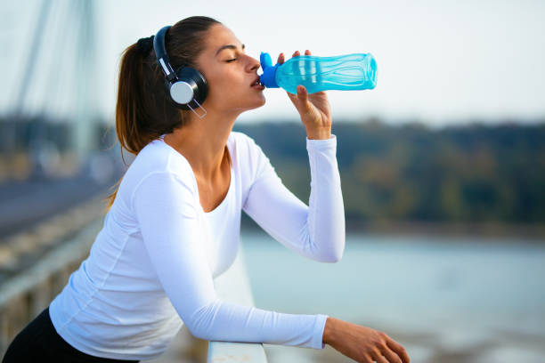 istock Athlete woman drinking water after running 1127749355