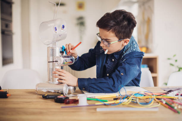 istock Boy making robot toy of recycling material 1127750400