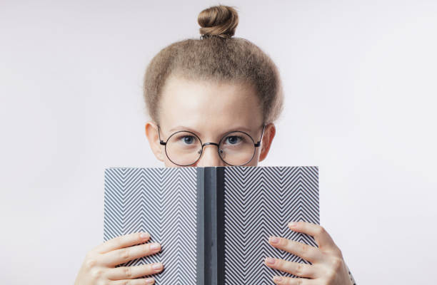 istock scared girl hiding behind the book 1127751259