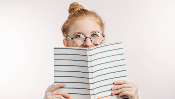 istock cheerful cunning student pretending that she is reading book 1127754865