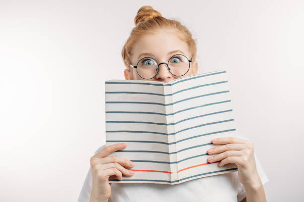 istock surprised girl holding a book. 1127755316