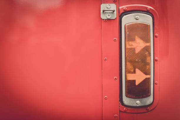 Close up shot of a vintage turn signal light of a red bus.