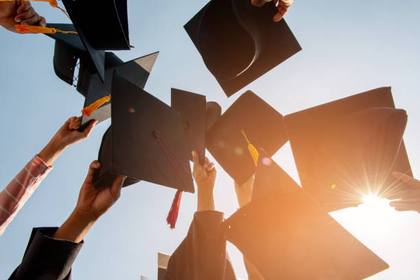 istock Black hat of the graduates floating in the sky. 1127760311