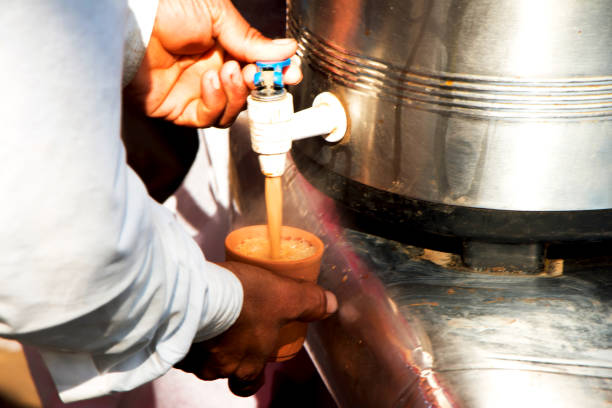 istock Man filling a cup with tea from a container 1127763210