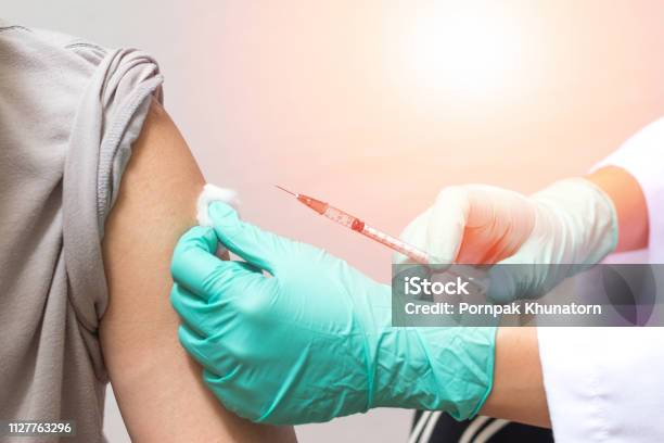 Vaccination Healthcare Concept Hands Of Doctor Or Nurse In Medical Gloves Injecting A Shot Of Vaccine To A Man Patient Stock Photo - Download Image Now