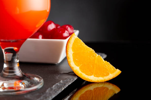 Detail of cold tequila sunrise cocktails with tequila, pomegranate juice and orange juice decorated with slices of orange and maraschino cherries