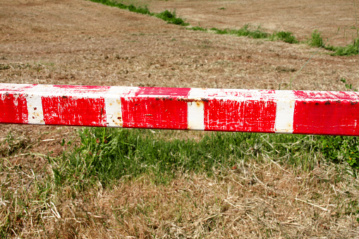 Warning sign, detail of red and white sign barrier on green grass in nature, close up. Transport and traffic regulation. Old fence made and white and red street parking barrier ramp and control point.