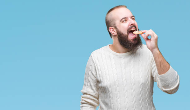 istock Young hipster man eating chocolate chips cookie over isolated background with a confident expression on smart face thinking serious 1127774362