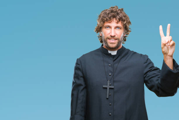 istock Handsome hispanic catholic priest man over isolated background showing and pointing up with fingers number two while smiling confident and happy. 1127775420