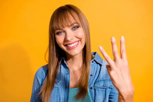 Close-up portrait of her she nice cute sweet lovely winsome fascinating attractive cheerful straight-haired lady showing 3 middle fingers isolated over bright vivid shine yellow background