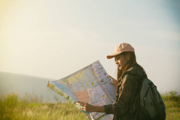 istock Side View Of Woman Reading Map On Field Against Sky 1127779699