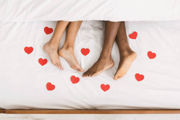 毛布の下のベッドに横になっているカップルの足を愛する - bed couple human foot heterosexual couple ストックフォトと画像