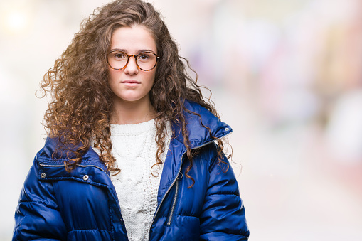 Beautiful Young Brunette Curly Hair Girl Wearing Winter Coat Glasses And Sweater Over Isolated Background With Serious Expression On Face Simple And Natural Looking At The Camera Stock Photo - Download Image Beautiful Young Brunette Curly Hair Girl Wearing Winter Coat Glasses And Sweater Over Isolated Background With Serious Expression On Face Simple And Natural Looking At The Camera Stock Photo - Download Image