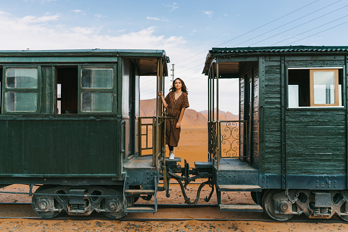 Young Caucasian woman in dress standing in old-fashioned train in Wadi Rum