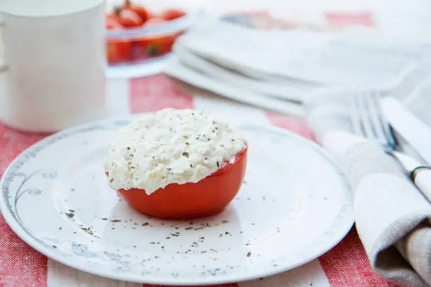 Vilnius, Lithuania - Aug 18, 2011: a halved tomato stuffed with spiced fresh homemade cottage cheese (farmer's cheese) and baked in the oven. Follows paleo diet and Hay diet rules. Only protein and vegetables.
