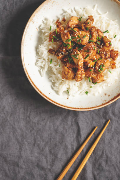 istock Top view on sesame chicken pieces with rice on a ceramic plate. Chinese traditional dish. Copy space. 1127788261