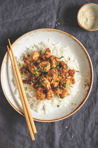 istock Top view on sesame chicken pieces  with rice on a ceramic plate. Chinese traditional dish. 1127788324