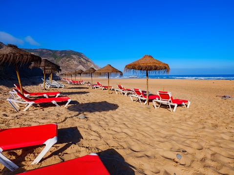 Beach with straw umbrellas and deck chairs