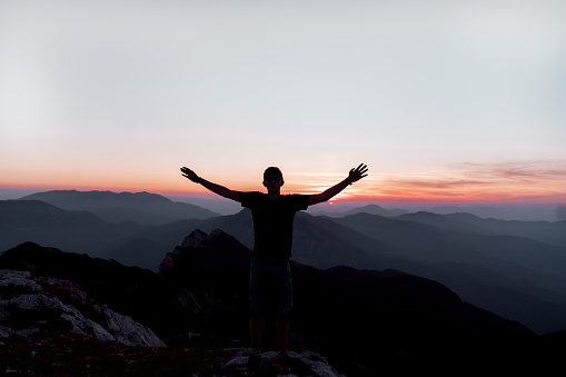 Young man at a mountain peak enjoying the sunrise view