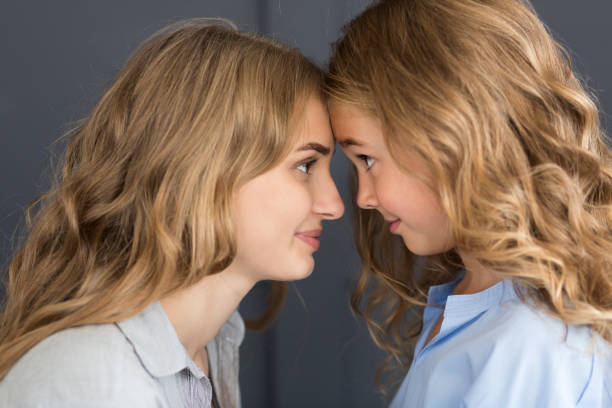 istock Cute girl and her young mom touching foreheads 1127798346