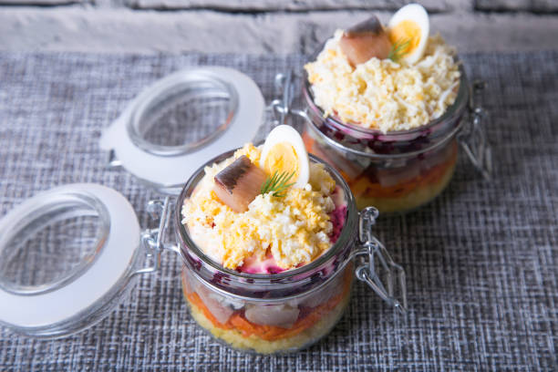 Herring under a fur coat. Traditional Russian multi-layered salad of herring, beets, potatoes, carrots and eggs. Close-up, selective focus.