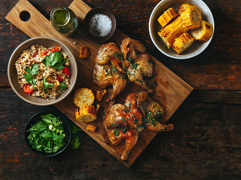 Grilled whole butterflied chickens with vegetables, chimichurri sauce and quinoa salad