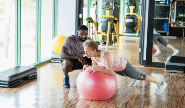 istock Personal trainer helping senior woman at gym 1127800969